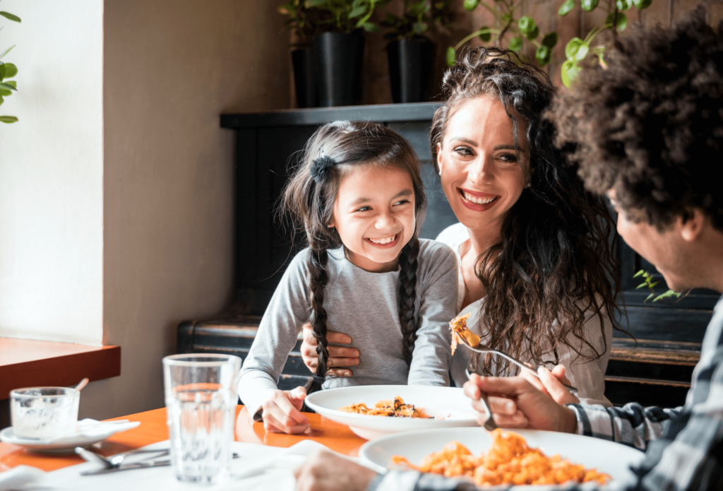 Smiling family in kitchen with text overlay: Take Meal Planning Off Your Plate - Nourish Culinary’s Personal Chef Services.